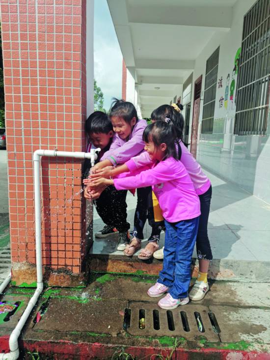 廣西僑聯及廣西華僑愛心基金會為玉林市陸川縣東西村小學打井，解決孩子健康安全飲水問題。圖為孩子們在干淨的水前露出了快樂的笑容.jpg