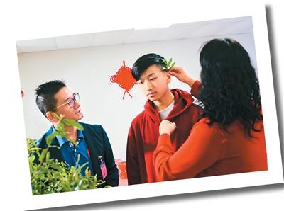 加拿大溫哥華潮籍青少年“出花園”成人禮上，朱春雄（左）與妻子（右）為兒子朱焯森（中）插上石榴枝葉。受訪者供圖